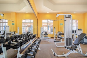 Une salle de sport équipée de matériel de musculation, d’appareils d’exercice et d’haltères.