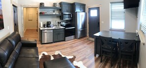 Modern kitchen with stainless steel appliances, dining area, and seating space.