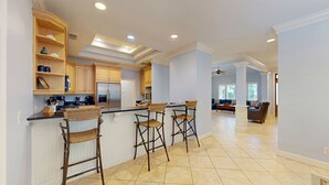 A spacious kitchen with a central island, wooden cabinets, and a built-in oven. There are three bar stools at the island.