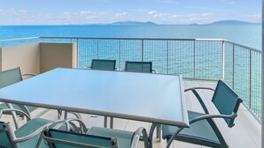 A balcony with a table and chairs, overlooking a body of water and distant land. - 1 Bright Point Apartment 4502 (Nelly Bay)