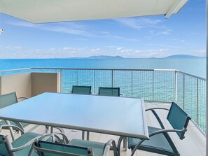 A balcony with a table and chairs, overlooking a body of water and distant land. - 1 Bright Point Apartment 4502 (Nelly Bay)