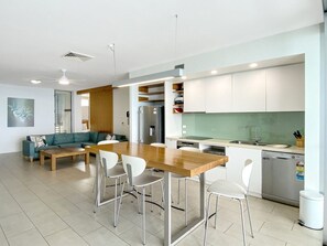 A modern kitchen with a wooden island, white chairs, and a built-in dishwasher. - 1 Bright Point Apartment 4502 (Nelly Bay)