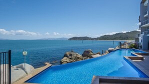 A swimming pool with a view of the sea and a distant island. - 1 Bright Point Apartment 4502 (Nelly Bay)