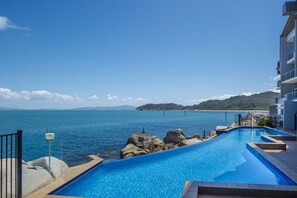 A swimming pool with a view of the sea and a distant island. - 1 Bright Point Apartment 4502 (Nelly Bay)