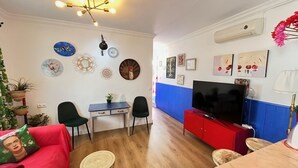 Un saló amb televisió, parets vermelles i blaves, un terra de fusta i diverses decoracions murals.