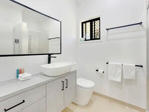 Une salle de bain moderne avec un lavabo, des toilettes et une douche, le tout de couleur blanche.