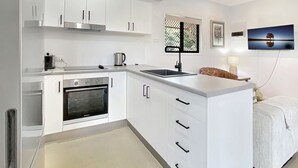 Eine moderne Küche mit weißen Schränken, einem eingebauten Backofen, einer Mikrowelle und einer großen Kochinsel mit Spüle.