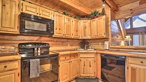 Una cocina tipo cabaña de madera con microondas, estufa y lavavajillas integrados.
