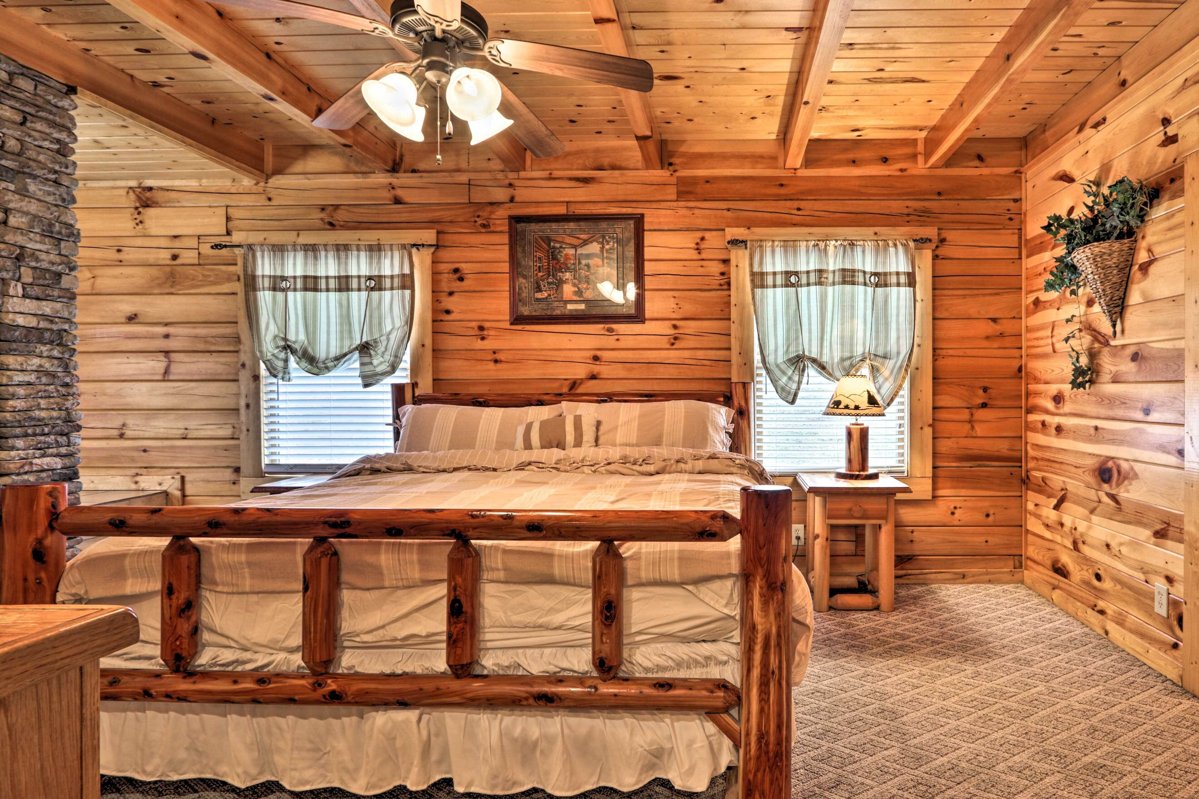Ein Schlafzimmer einer Holzhütte mit einem Bett, einem Deckenventilator und einem gerahmten Bild an der Wand.