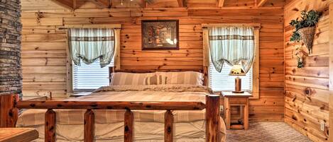 Ein Schlafzimmer einer Holzhütte mit einem Bett, einem Deckenventilator und einem gerahmten Bild an der Wand.