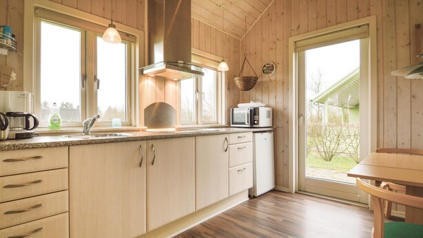 Een keuken met houten kastjes, een magnetron, een waterkoker en een spoelbak.