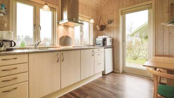 Une cuisine équipée de meubles en bois, d’un four à micro-ondes, d’une bouilloire et d’un évier.