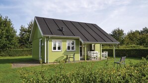 Een groen huis met een schuin dak, een veranda met buiten zitplaatsen en een verzorgd gazon.
