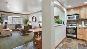 A living room with a dining table, chairs, and a fireplace. There is a kitchen with wooden cabinets, a stove, and a microwave. - Mtn Villa Retreat~Hot Spring, Skiing & Park City Villa 2018-1 (Midway)