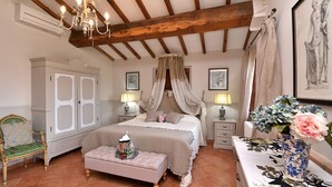 Une chambre à coucher avec un grand lit, une table de chevet, une chaise, une armoire et un lustre.