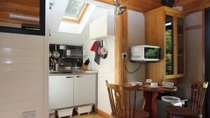 A compact kitchen with a skylight, wooden cabinets, and a dining area with two wooden chairs.