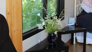 A room with a black table holding a vase of flowers. A window with a view of greenery is visible.