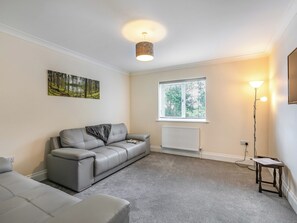 A modern living room with a grey sofa, a small table, a floor lamp, and a window with blinds. - Dawson Park 9 - UK12668 (Mablethorpe)