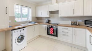 A modern kitchen with white cabinets, a built-in washing machine, a microwave, and a toaster.
