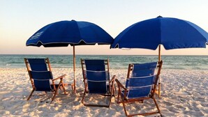 Three beach chairs with blue umbrellas on a sandy beach. - Penthouse Unit- Large Private Beach! (Miramar Beach)
