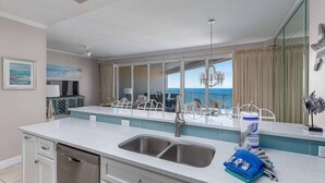 A modern kitchen with a large island, stainless steel appliances, and a view of the ocean. - Penthouse Unit- Large Private Beach! (Miramar Beach)
