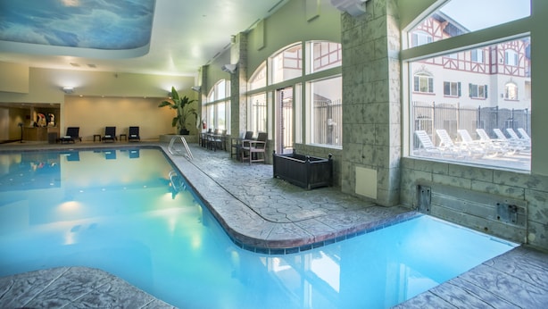 An indoor swimming pool with clear blue water, stone-tiled edges, and lounge chairs along the walls. - Family Getaway~Pool, Tubing, Skiing, & Ice Castles Villa 1063 (Midway)