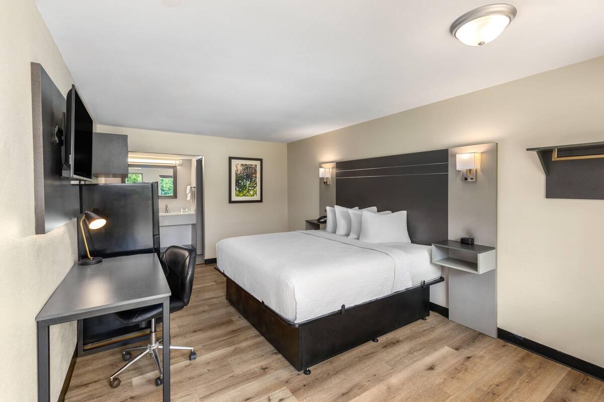 Ett modernt hotellrum med en säng, ett skrivbord och en stol.