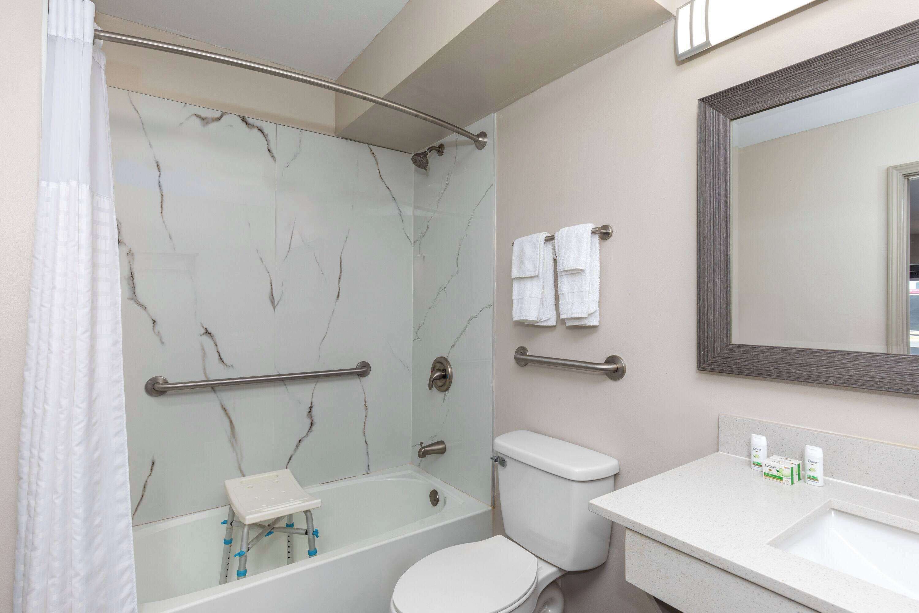 A bathroom with a glass-enclosed shower, a white toilet, and a sink with toiletries.
