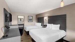 A hotel room with two beds, a desk, a TV, a mirror, and a picture on the wall. - Baymont by Wyndham Dothan (Dothan)