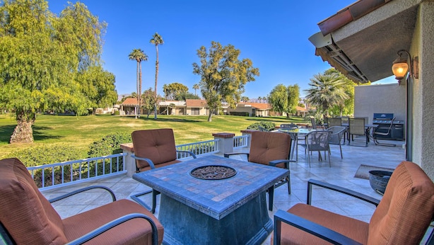 An outdoor patio with a stone table and chairs, a grill, and a view of a well-maintained lawn and trees. - Updated Palm Desert Escape w/ Resort Amenities! (Palm Desert)