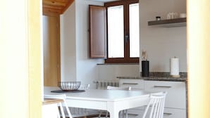 A modern kitchen with white cabinetry, a wooden ceiling, and a white dining table with chairs.