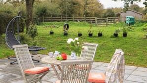 An outdoor patio with a round table, two chairs, and a grill. - GLAN ABER, pet friendly, character holiday cottage in Llaneilian (Llaneilian)