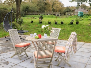 An outdoor patio with a round table, two chairs, and a grill. - GLAN ABER, pet friendly, character holiday cottage in Llaneilian (Llaneilian)