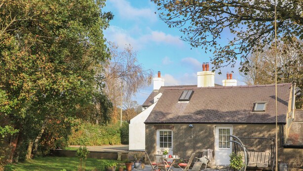 A stone house with a tiled patio, surrounded by potted plants and a grassy lawn. - GLAN ABER, pet friendly, character holiday cottage in Llaneilian (Llaneilian)