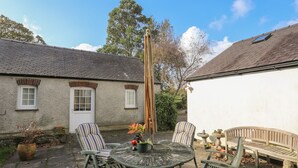 A patio with a round table, two striped chairs, a bench, and a tall wooden pole. - GLAN ABER, pet friendly, character holiday cottage in Llaneilian (Llaneilian)