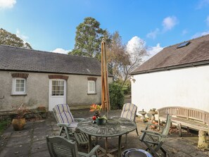 A patio with a round table, two striped chairs, a bench, and a tall wooden pole. - GLAN ABER, pet friendly, character holiday cottage in Llaneilian (Llaneilian)