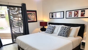 Une chambre d’hôtel avec un grand lit, une table de chevet, une lampe et une porte donnant sur un espace extérieur.