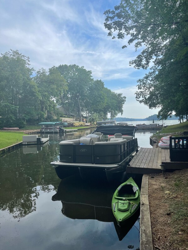 A calm lake with a dock, a green kayak, and a motorboat.