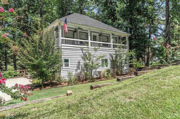 A two-story house with a balcony, surrounded by trees and a grassy yard.