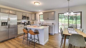 Een moderne keuken met een centraal eiland, roestvrijstalen apparatuur en een eethoek met uitzicht.