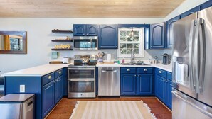 Eine moderne Küche mit blauen Schränken, Edelstahlgeräten und einer Holzbalkendecke.