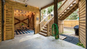 Eine Holztreppe führt zu einem überdachten Außenbereich mit Tisch und Stühlen, umgeben von Holzwänden und einer Holzterrasse.