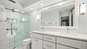 A modern bathroom with a glass shower enclosure, a white toilet, and a large mirror above a white vanity with multiple drawers. - Cozy Dockside 2 bed, 2 bath at Sanibel Moorings #1422 (Sanibel)