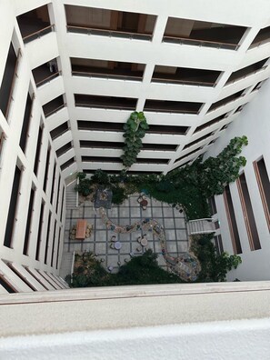 Ein mehrgeschossiges Atrium mit Innenhof, Sitzgelegenheiten und viel Grün.
