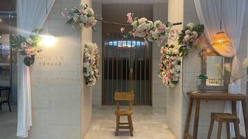 A reception area with a wooden chair, a small table, and floral decorations.