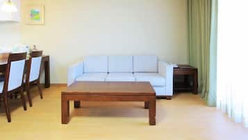 A living room with a wooden coffee table, a white sofa, and a dining table with chairs.