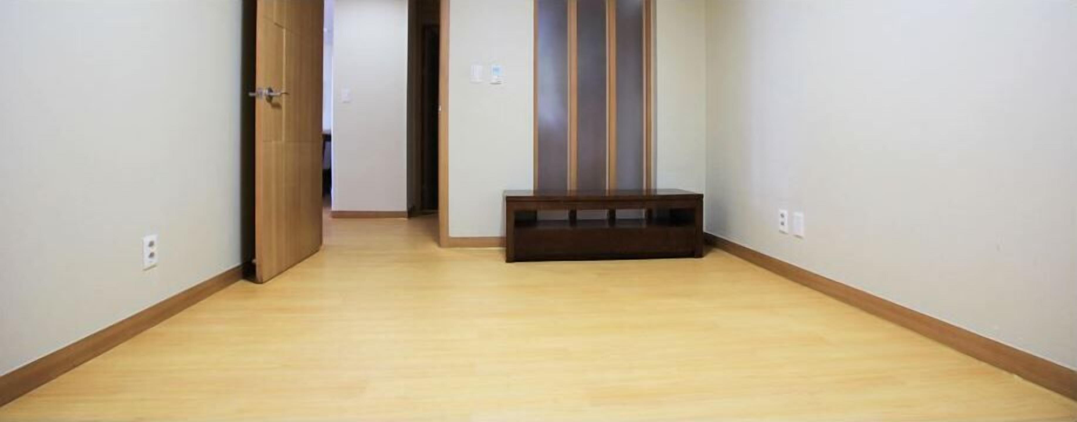 Un pasillo con piso de madera y un banco.