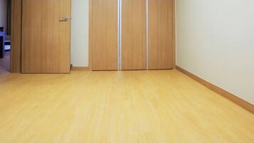 A room with a wooden floor, a door, and a white wall.