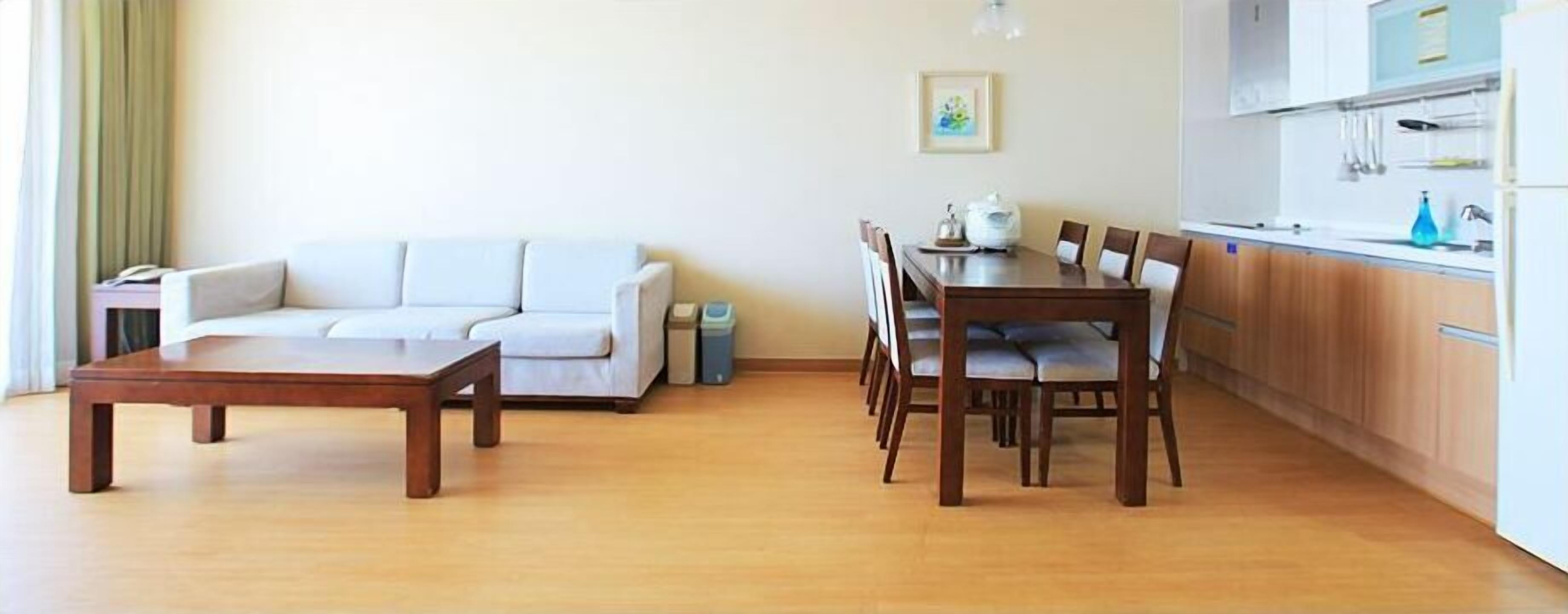 A living room with a sofa, a wooden coffee table, and a dining area with a table and chairs.