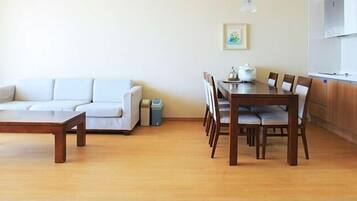 A living room with a sofa, a wooden coffee table, and a dining area with a table and chairs.